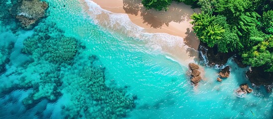 Stunning aerial view of a tropical beach with clear turquoise water, vibrant coral reefs, and lush green foliage.