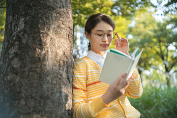 a woman reading a book in the park in the fall