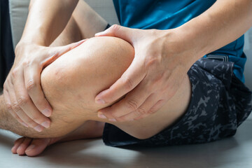 man with knee pain, he puts his hand on his knee, pain point from osteoarthritis and...