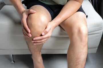 man with knee pain, he puts his hand on his knee, pain point from osteoarthritis and...
