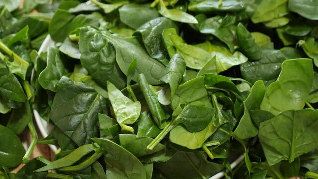 Fresh green spinach leaves on wooden table and in a bowl. High quality 4k footage