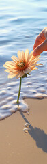 A hand gently touches a beautiful flower growing in the sand near the water's edge, showcasing nature's delicate balance and tranquility.