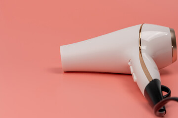 Hair dryer for drying hair on a pink background. The buttons are labeled 