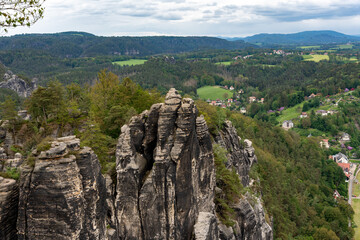 A mountain range with a town in the distance. The mountains are covered in trees and the town is small and quaint