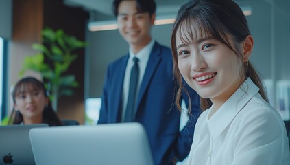 A group of Japanese business people in their thirties, smiling and having an online meeting with each other at the office table