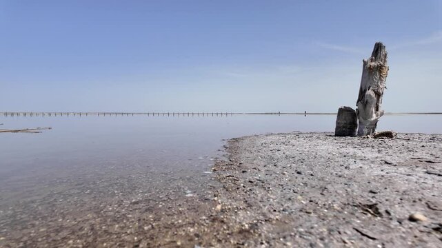 A peaceful shot of a pink lake in the afternoon. The water is calm and the sky is blue.