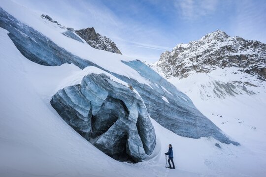 Winter landscape view of a snowshoes' hiker in front of a collapsed ice cave