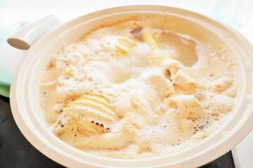 土鍋でアク抜きのため米ヌカと一緒に熱湯で茹でられている筍