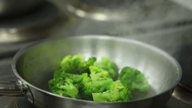 A Chief cooks broccoli on a grill close up shot, insert shot