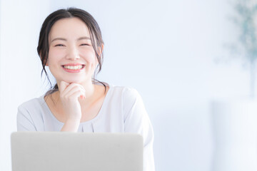 メインビジュアルにも！パソコンを操作する若い女性　カメラ目線の笑顔
