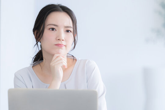 パソコン作業をする若い女性　考える悩むの頬杖のポーズ
