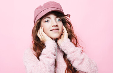 People, childhood and fashion concept: little girl child wearing pink sweater and hat over pink background.