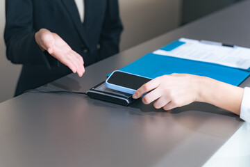 Close-up of a woman's hands paying by touching her smartphone at the cash register