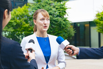 A white woman being interviewed in front of a building
