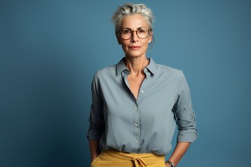 Fototapeta premium A woman in a blue shirt and yellow pants stands in front of a blue wall