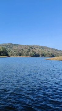 Boating on a blue periyar lake in kerala, india. Periyar Tiger Reserve offers 1.5 hrs boating trips at the lake near the sanctuary. Blue travel background having water, forest and sky in a sunny day