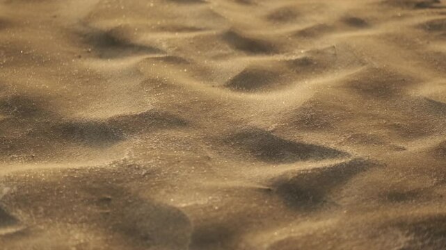 Close up shot of sand being blown into dune shapes