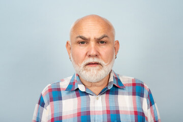 Elderly caucasian old man face. Old mature senior man with grey beard on grey studio background.