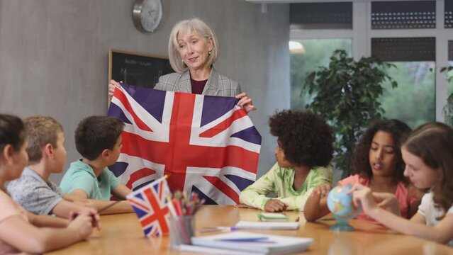 High school teacher holds the national flag of Great Britain in her hands and tells the pupils the history of the country. . High quality 4k footage