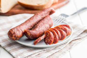 Sliced smoked salami sausage on plate.