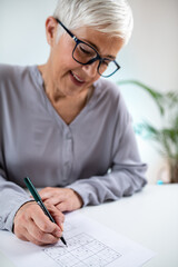 A senior woman engages in cognitive training by solving Sudoku puzzles, enhancing mental acuity and...