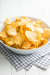 Crispy Potato Chips in bowl on white table.