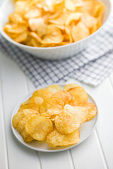 Crispy Potato Chips on plate on white table.