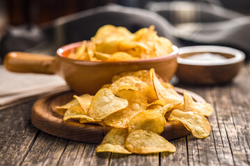 Crispy Potato Chips on cutting board on wooden table.