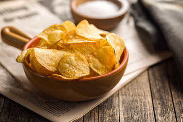Crispy Potato Chips in bowl on wooden table.