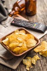 Bowl of Potato Chips on Wooden Table With Remote and Beer Bottles
