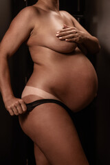 Pregnant woman pulls back her panties showing instant tan. Vertical photo. 