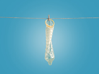 Condom hanging on clothesline with blue background symbolizing sexual health and contraception