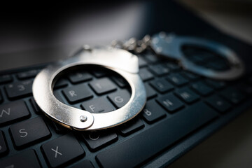 metal handcuffs on a black keyboard. Selective focus on handcuffs on a keyboard cyber crime, hacking, bullying Against law concept in dark low key tone © diy13