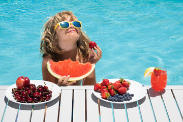 Child eat watermelon. Kid with summer fruits in pool. Portrait of summer kids. Child in swimming...