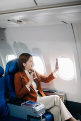Naklejka premium ￼Asian woman sitting in a seat in airplane and looking out the window going on a trip vacation travel concept.Capture the allure