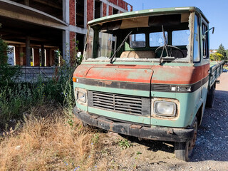 Cruel Destiny. Abandoned Green  Truck and Unfinished Building on a Sunny Morning.