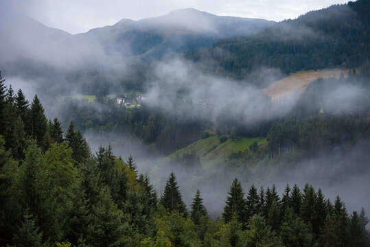 Morning mist rising over Alpine valley in autumn colorful countryside
