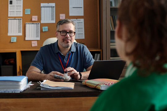 Smiling coach discussing with student at desk