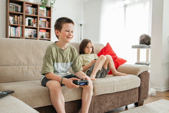 Smiling boy holding console and playing video game at home