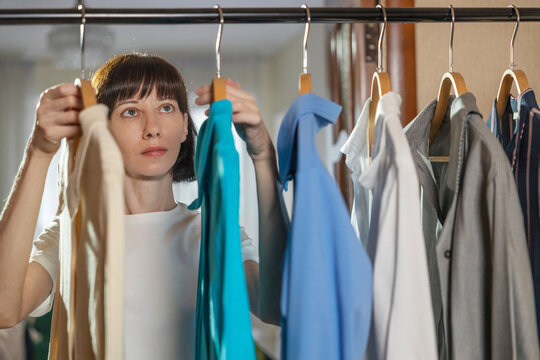 Woman hanging ironed clothes on rack at home
