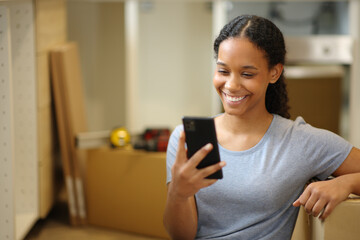 Happy black woman moving home checking phone