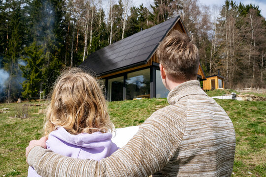 Couple with floor plan looking at modern house near forest