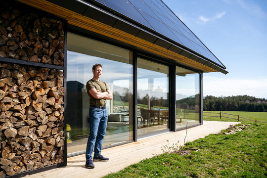 Man standing with arms crossed at patio of modern house
