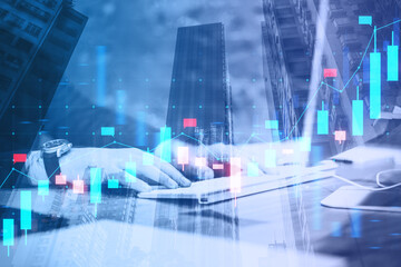 Close up of male hands using laptop with glowing blue candlestick forex chart on blurry city background. Financial growth, stock and exchange concept. Double exposure.