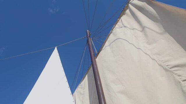 White sails close-up on a background of blue sky with clouds. Yachting and sailing. Summer vacation and travel at sea