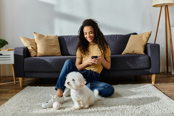 Woman sitting beside her fluffy Bichon Frise on the floor.