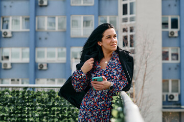 Fototapeta premium Businesswoman in Black Suit Using Smartphone on Break in Modern Urban Environment.