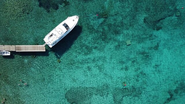 Nautical Tourism, Yacht moored to wooden Jetty in clear blue Lagoon, Drone top down