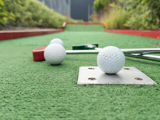 colorful golf putters with golf balls on synthetic grass