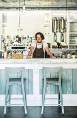 Handsome barista working in coffee shop, standing behind counter, bar. University student working...